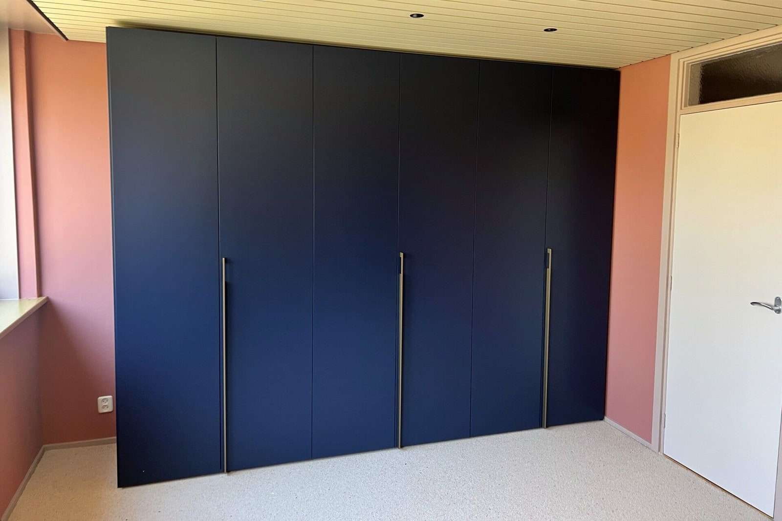 Een donkerblauwe kledingkast op maat tot aan het plafond